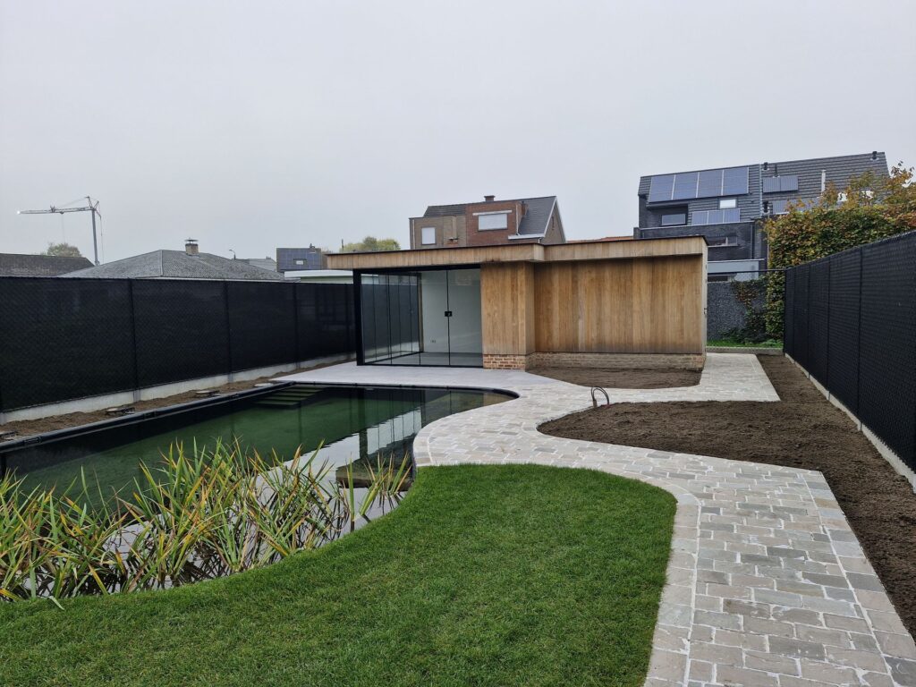 Glazen schuifwand in moderne bijbouw met houten gevel en uitzicht op natuurlijke zwemvijver.